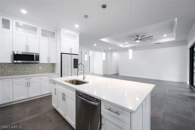 kitchen with ceiling fan, sink, stainless steel appliances, a raised ceiling, and pendant lighting