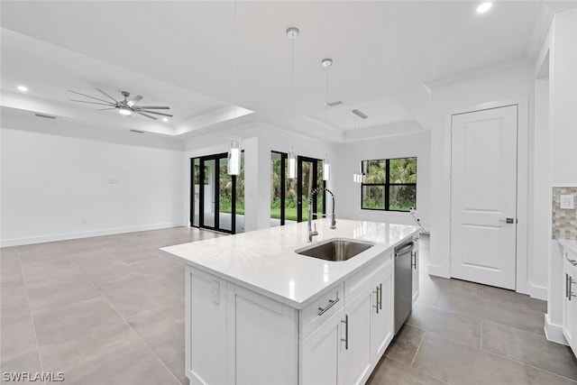 kitchen with pendant lighting, a tray ceiling, ceiling fan, and a kitchen island with sink