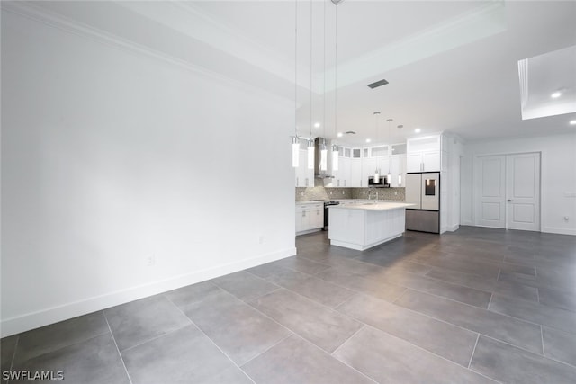 kitchen with pendant lighting, a raised ceiling, a kitchen island, wall chimney exhaust hood, and white cabinetry