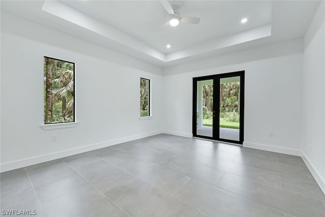 spare room with light tile flooring, a tray ceiling, ceiling fan, and french doors