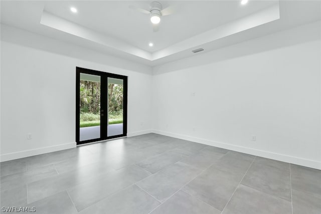 tiled spare room featuring french doors, ceiling fan, and a tray ceiling