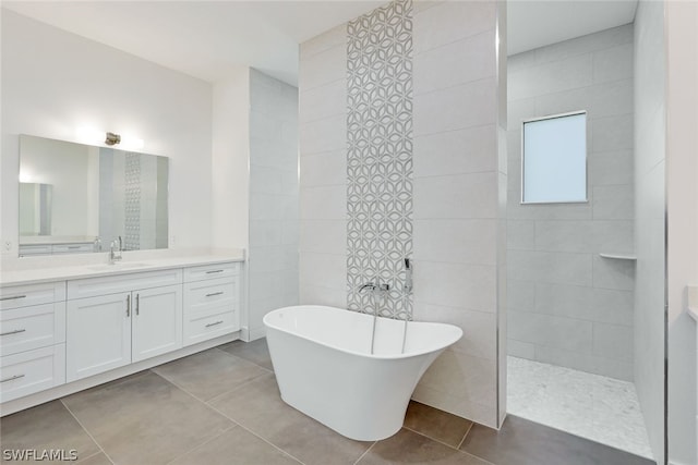 bathroom with tile walls, a bathtub, vanity, and tile flooring