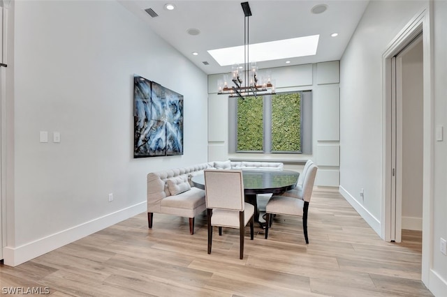 dining room featuring a skylight, light hardwood / wood-style floors, and an inviting chandelier