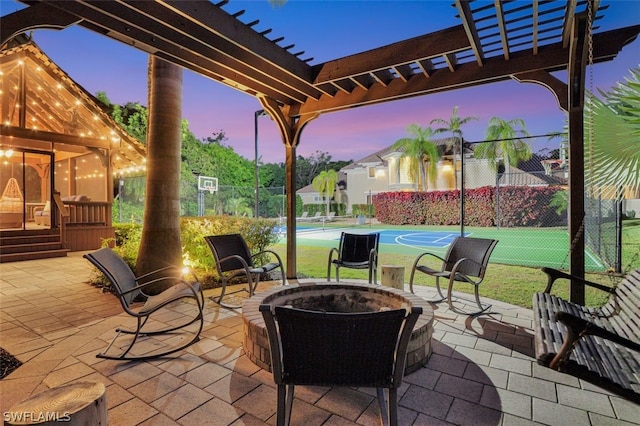 patio terrace at dusk featuring a fire pit, basketball court, and a pergola