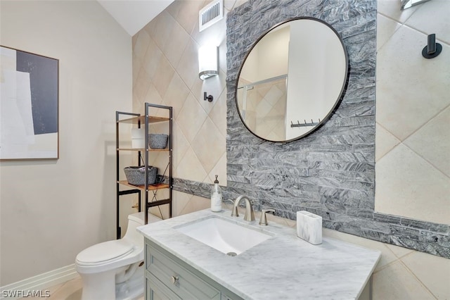 bathroom featuring tile walls, oversized vanity, toilet, and tile floors