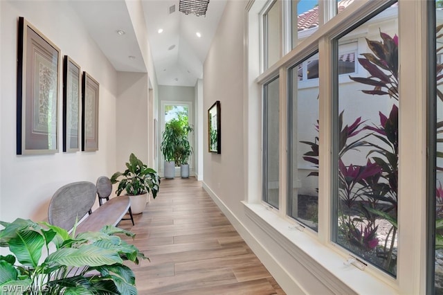 hall with high vaulted ceiling and light hardwood / wood-style flooring