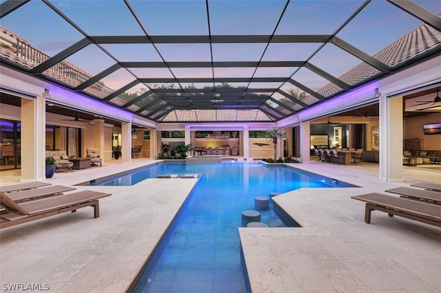 pool at dusk with glass enclosure, an outdoor living space, and a patio