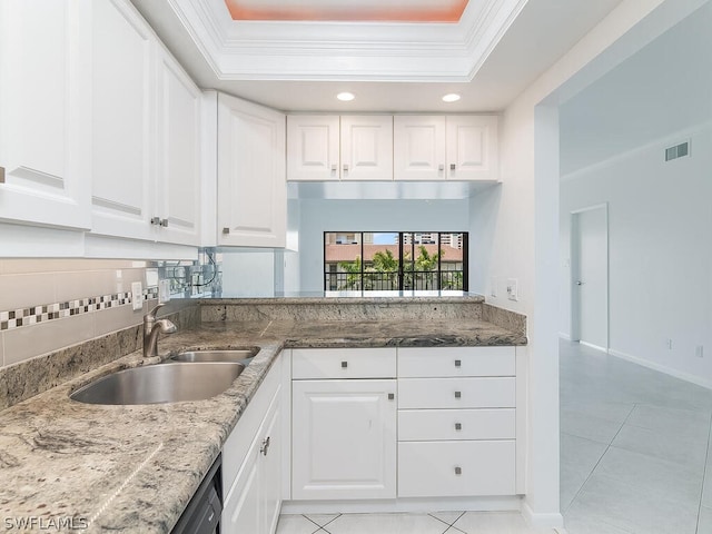 kitchen with white cabinetry, a tray ceiling, crown molding, sink, and light tile patterned floors