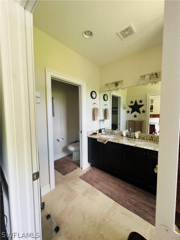 bathroom with baseboards, visible vents, vanity, and toilet