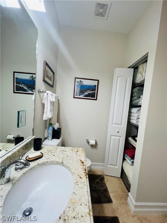 bathroom featuring baseboards, visible vents, vanity, and toilet