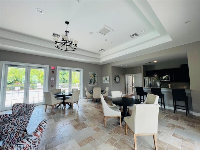 dining space featuring a tray ceiling, french doors, stone tile flooring, and baseboards