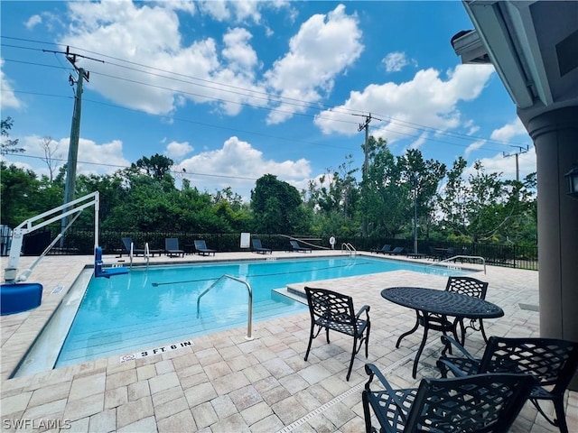 community pool with a patio area and fence