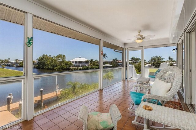 sunroom with ceiling fan and a water view