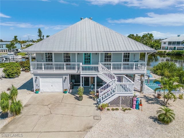 back of property with a water view, a porch, and a garage