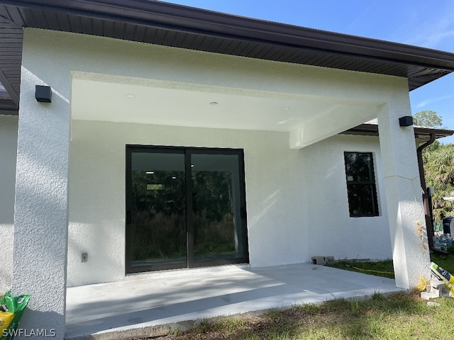 view of exterior entry with a patio area