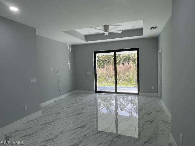 unfurnished room featuring ceiling fan, a raised ceiling, and light tile floors