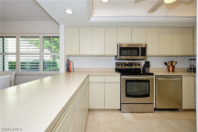 kitchen with kitchen peninsula, cream cabinetry, stainless steel appliances, and ceiling fan