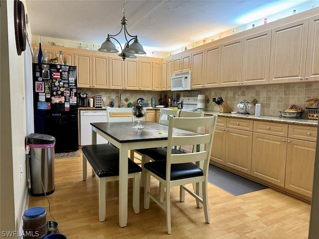 kitchen with light stone countertops, decorative light fixtures, white appliances, light wood-type flooring, and tasteful backsplash