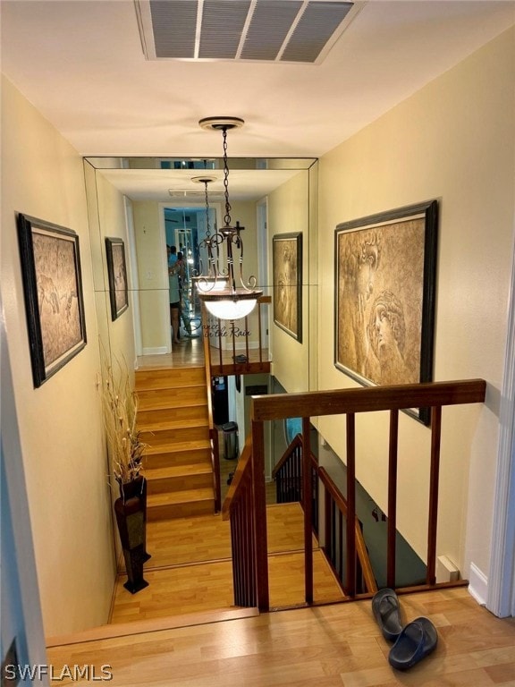 stairway with an inviting chandelier and light wood-type flooring