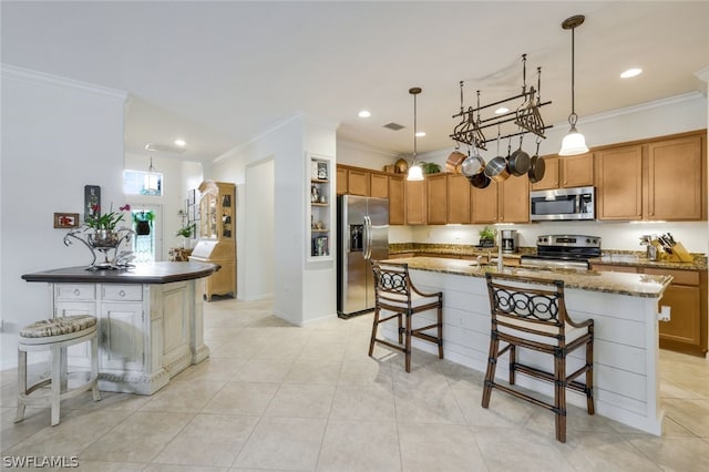 kitchen with stainless steel appliances, crown molding, decorative light fixtures, a breakfast bar area, and a center island with sink