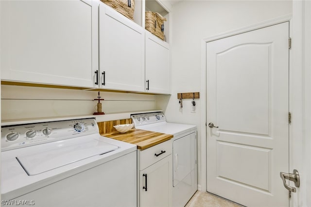 clothes washing area with washer and clothes dryer and cabinets