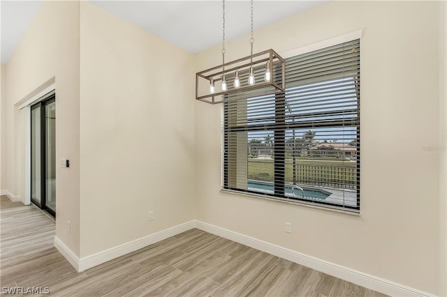 empty room featuring a chandelier and light wood-type flooring