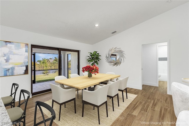 dining room with vaulted ceiling and light wood-type flooring