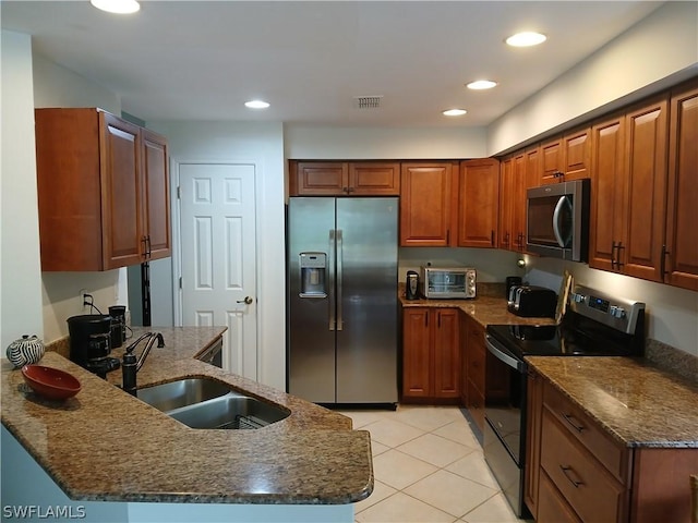 kitchen with dark stone countertops, sink, light tile patterned floors, and appliances with stainless steel finishes