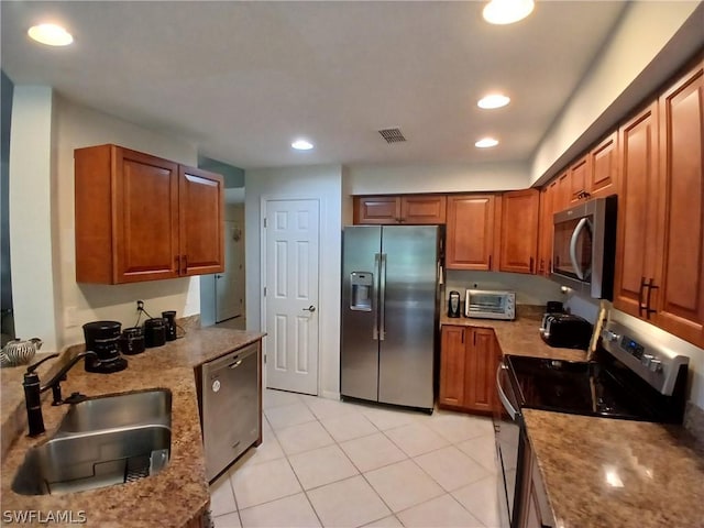 kitchen with light stone counters, sink, light tile patterned floors, and appliances with stainless steel finishes