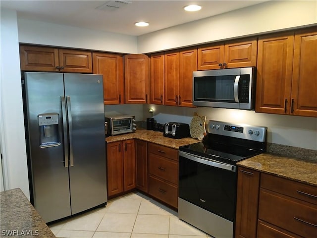 kitchen with light tile patterned flooring, stainless steel appliances, and stone counters