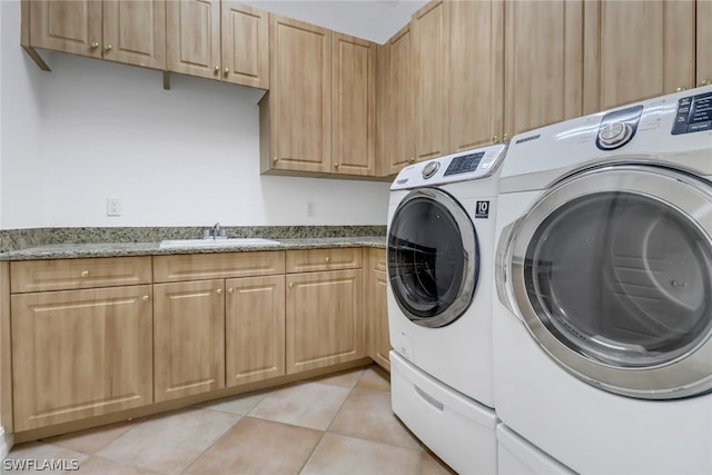 clothes washing area featuring separate washer and dryer, sink, light tile flooring, and cabinets