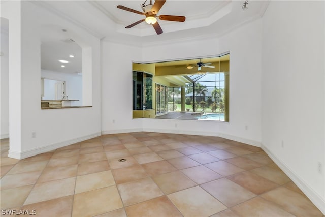 tiled spare room featuring ceiling fan, a raised ceiling, and ornamental molding