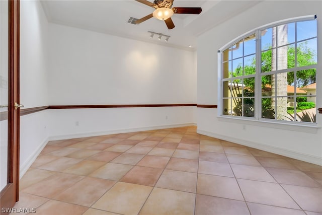 spare room featuring rail lighting, ceiling fan, and light tile flooring