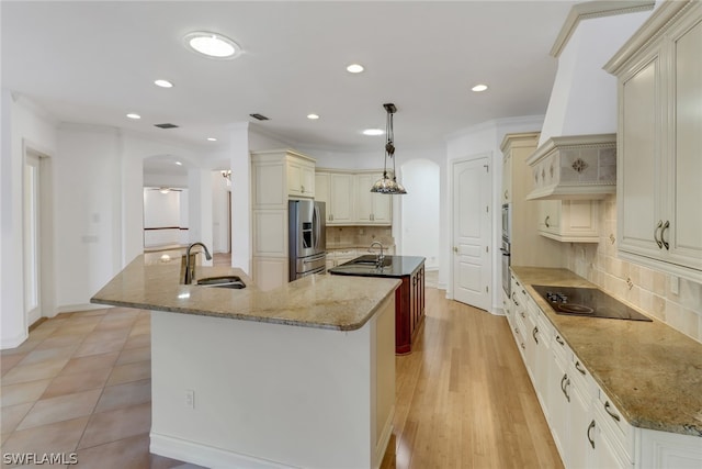 kitchen featuring custom range hood, appliances with stainless steel finishes, sink, decorative light fixtures, and tasteful backsplash