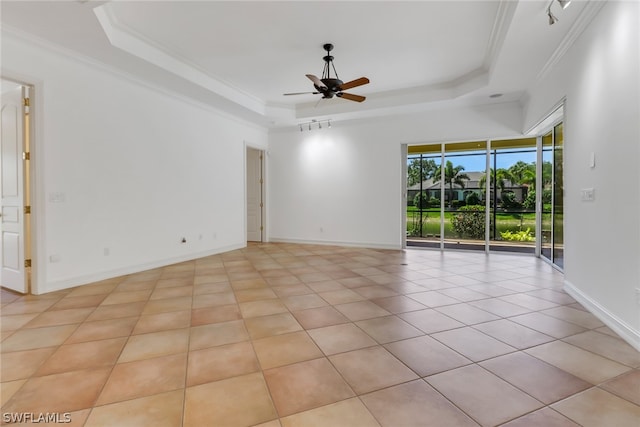 unfurnished room with ceiling fan, a raised ceiling, ornamental molding, and light tile floors