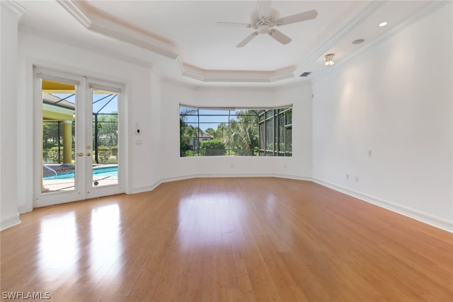 unfurnished room with french doors, light hardwood / wood-style flooring, a tray ceiling, and ceiling fan