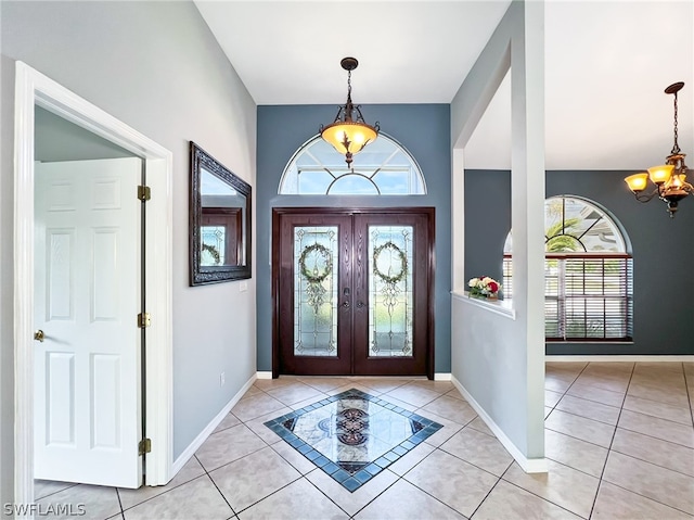 tiled entrance foyer with a notable chandelier, french doors, and a healthy amount of sunlight