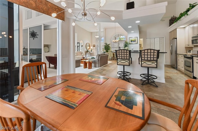 dining area with a notable chandelier, light tile flooring, and a high ceiling