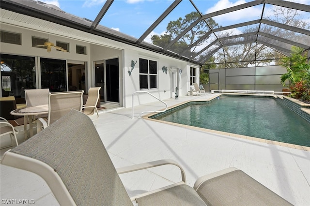 view of pool with glass enclosure, a patio area, and ceiling fan