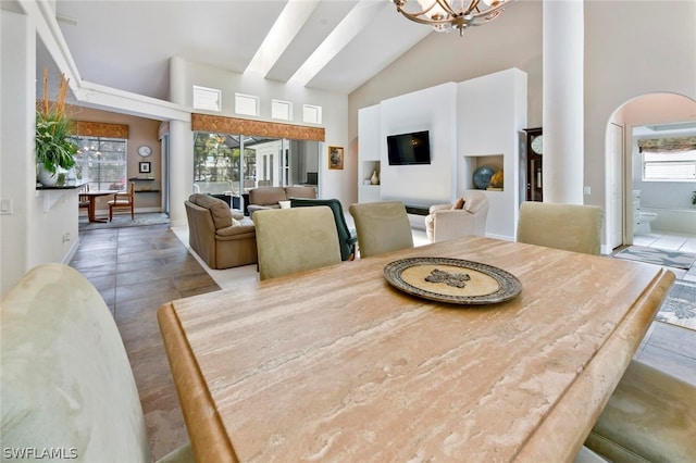 tiled dining space featuring high vaulted ceiling and a chandelier