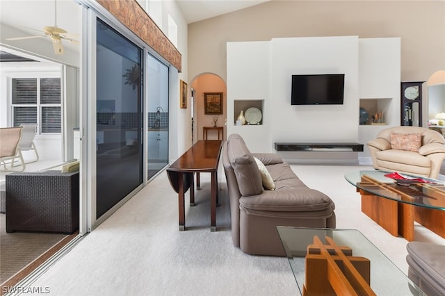 living room featuring lofted ceiling, ceiling fan, and light colored carpet