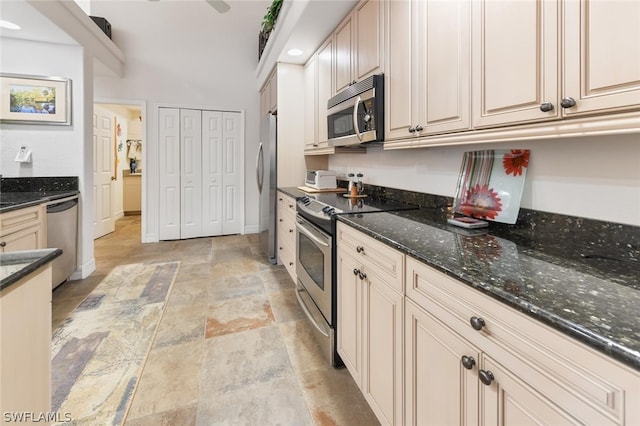 kitchen with stainless steel appliances, light tile floors, and dark stone countertops