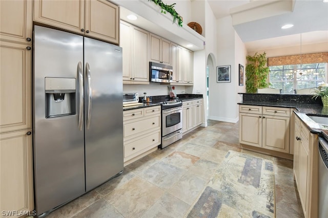 kitchen featuring dark stone counters, decorative light fixtures, light tile floors, stainless steel appliances, and sink