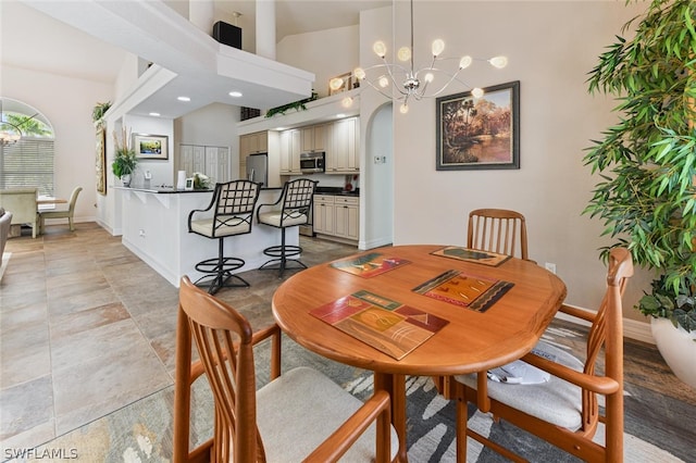 dining area with light tile flooring, high vaulted ceiling, and an inviting chandelier