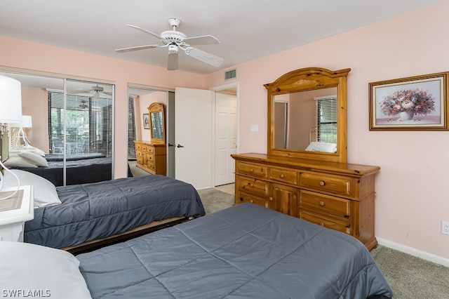 bedroom with dark carpet, two closets, and ceiling fan