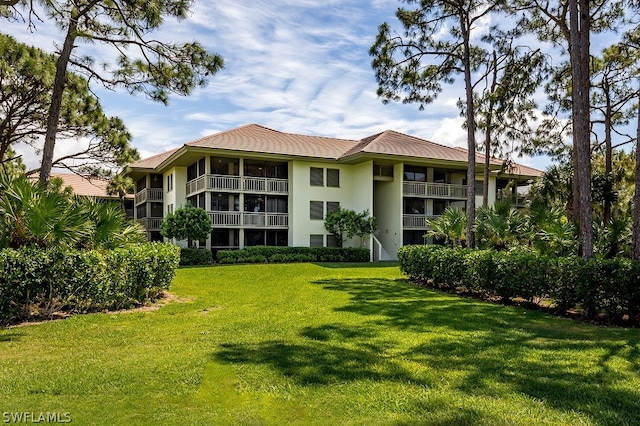 rear view of house featuring a balcony and a yard