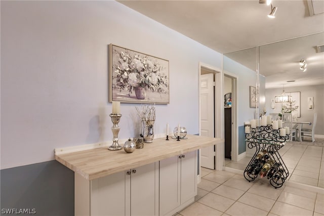 hallway featuring light tile flooring and a notable chandelier