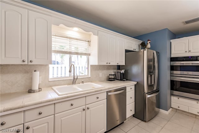 kitchen featuring sink, stainless steel appliances, backsplash, and white cabinets