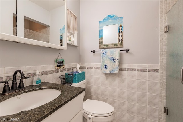 bathroom with tile walls, toilet, and vanity