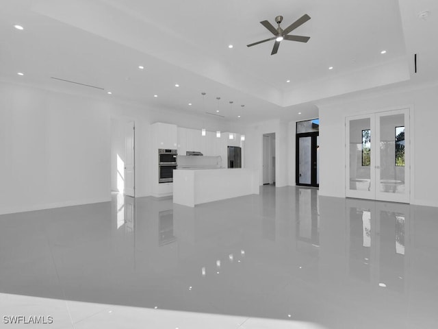 unfurnished living room with a raised ceiling, ceiling fan, and french doors